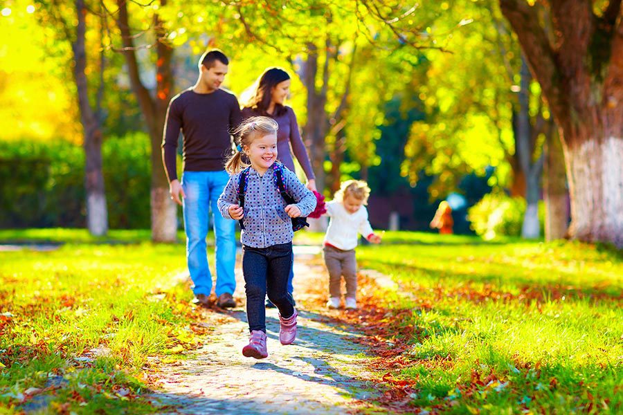 New Lexington, OH Insurance - Family Walks Their Kids Home From School on a Tree-Lined Sidewalk With Leaves Scattered Around